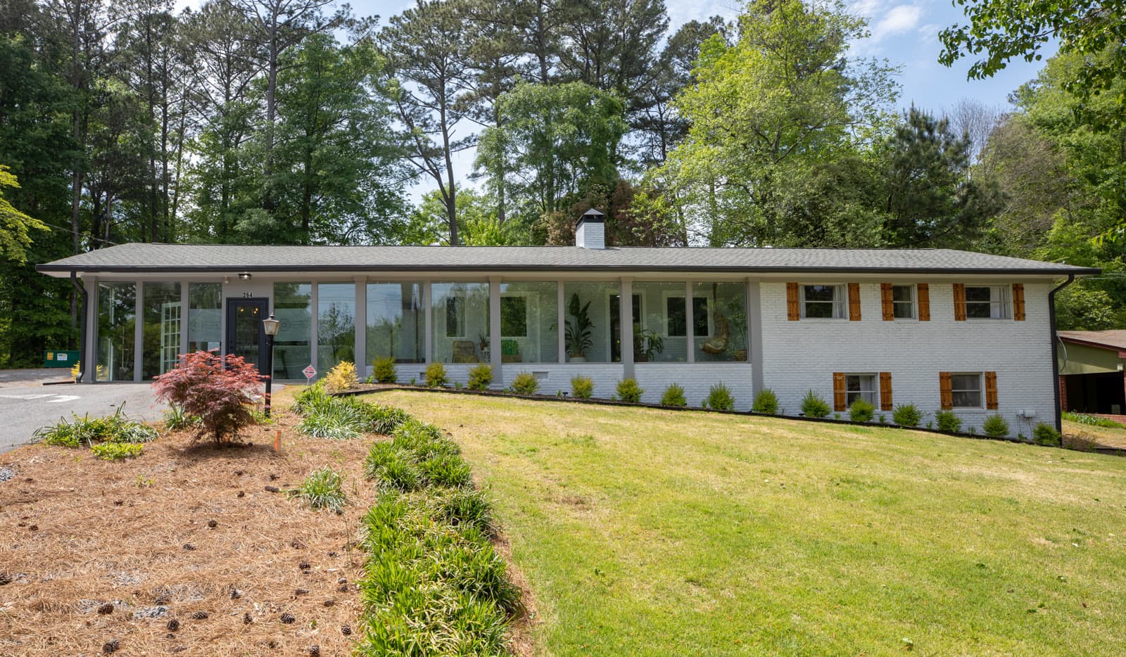 The practice from the street — a low white-brick building set back behind a lawn.