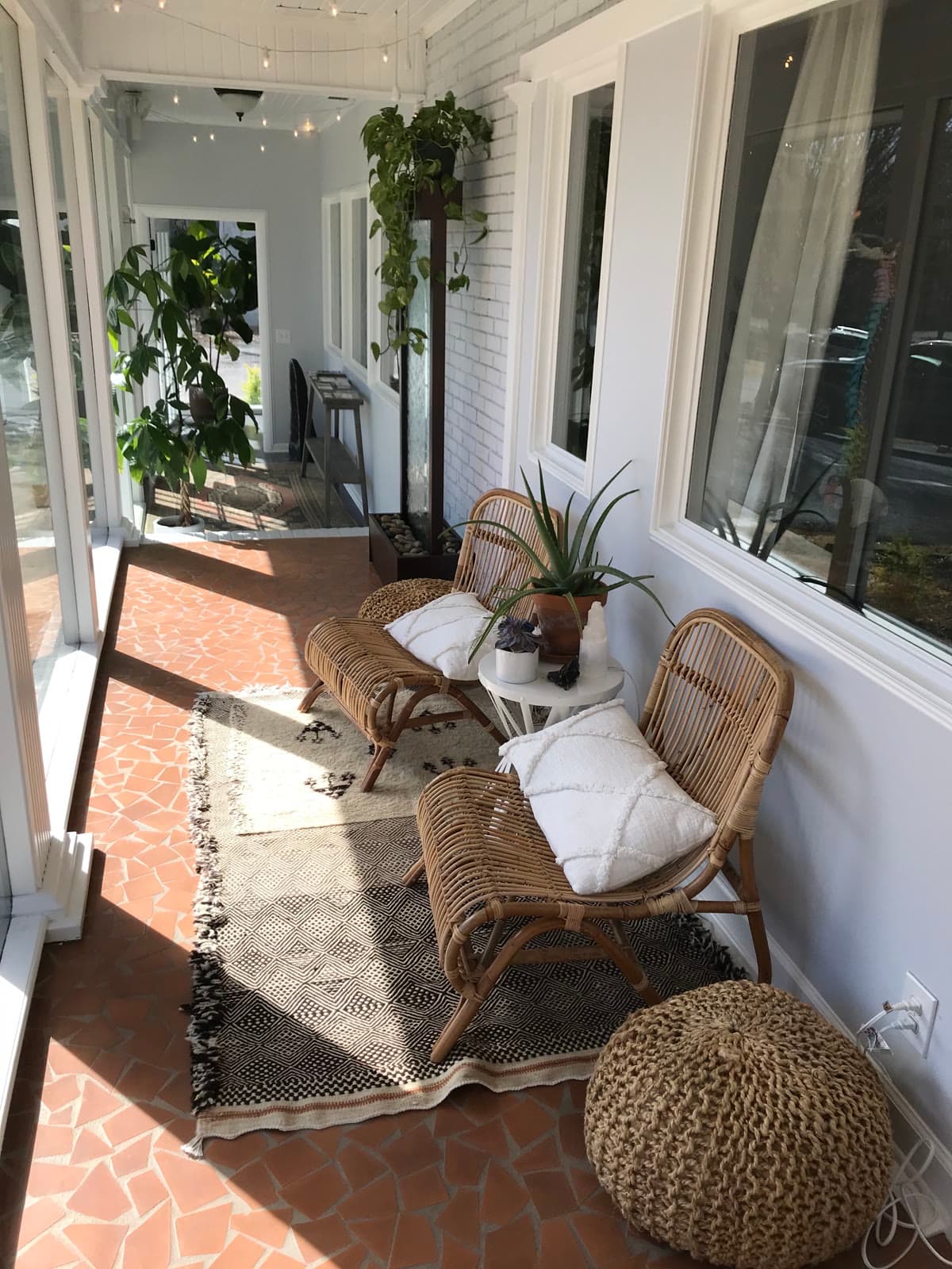 The sun porch inside the entrance, with rattan chairs and plants.